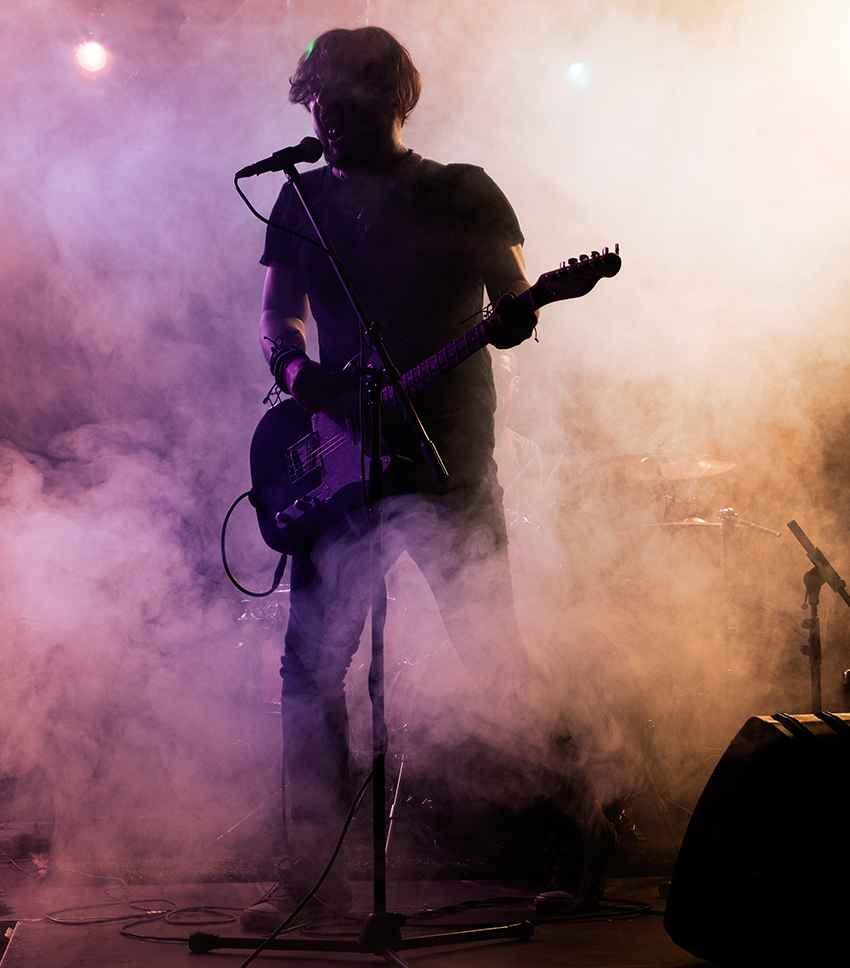 A man playing a guitar in a smoke filled room.